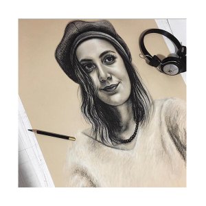 Künstlerische Porträtzeichnung einer Frau mit Barett neben Kopfhörern auf dem Zeichentisch, von Ferhat Tursun.